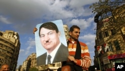 A protester holds a placard depicting Egyptian President Hosni Mubarak as Adolf Hitler in Cairo's Tahrir Square, January 31, 2011