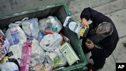 A man empties out the remains of an olive oil container from a trash bin in the northern Greek port city of Thessaloniki, Greece, January 4, 2011