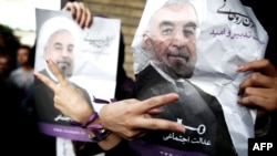 Iranian women flash the sign for victory as they hold portraits of moderate presidential candidate Hassan Rowhani during celebrations after he won the Islamic Republic's presidential elections in downtown Tehran on June 15, 2013. 