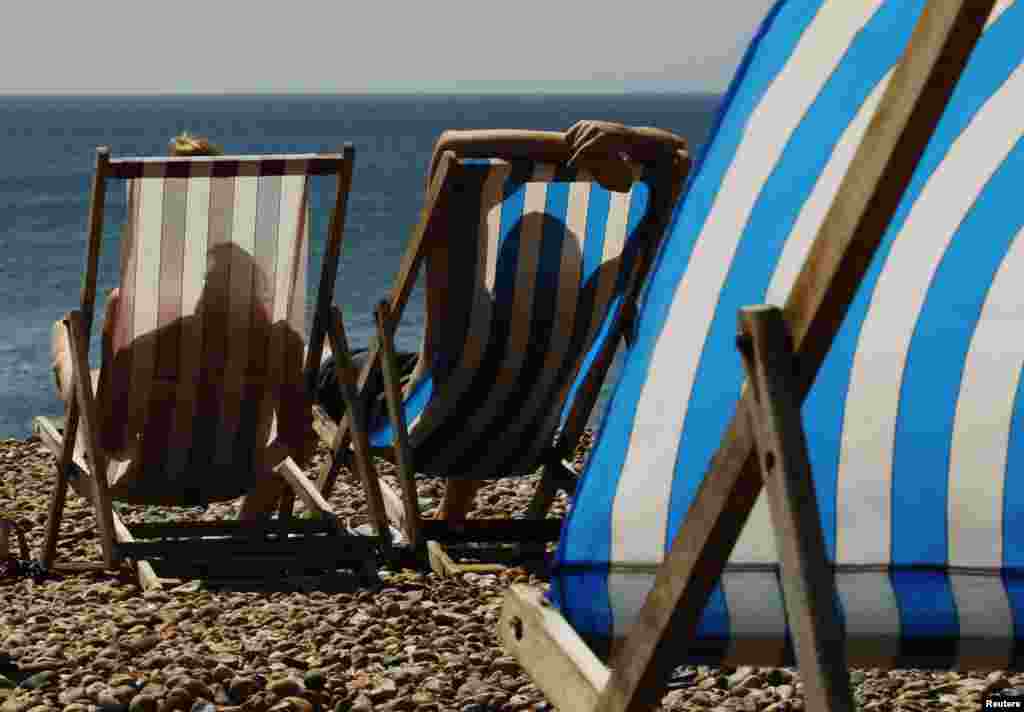 A couple sunbath in deck chairs on Brighton Beach, southern England. Britain&#39;s first prolonged heatwave in seven years has taken the country by surprise, with rails buckling, shops selling out of electric fans, and scientists estimating the surge in temperature could have caused hundreds of premature deaths.