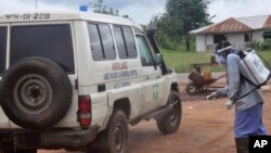 Petugas kesehatan menyemprotkan disinfektan pada ambulans yang digunakan untuk membawa dua orang yang diduga terjangkit virus Ebola di pinggiran kota Monrovia, Liberia (1/7). (AP/Abbas Dulleh)