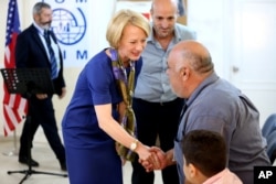 The U.S. ambassador to Jordan, Alice Wells, shakes hands with Syrian refugees ahead of their departure to the United States, Aug. 28, 2016.