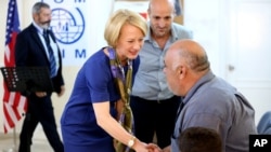 FILE - The U.S. ambassador to Jordan, Alice Wells, shakes hands with Syrian refugees ahead of their departure to the United States, Aug. 28, 2016.