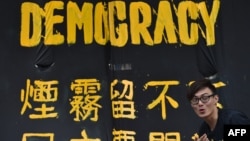 一位香港民主抗议者站在一条横幅前。（2014年9月30日）
