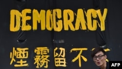 一名香港民主派抗议者站在横幅前。（2014年9月30日资料照）