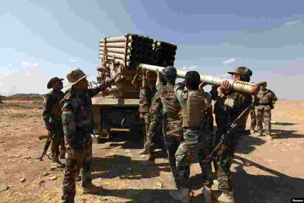 Iraqi Kurdish peshmerga troops load rockets into a launcher during fighting with Islamic State militants in Khazir, Sept. 16, 2014.