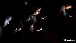 People surf the internet on their mobile devices at a hotspot in Havana, Cuba, July 10, 2018.