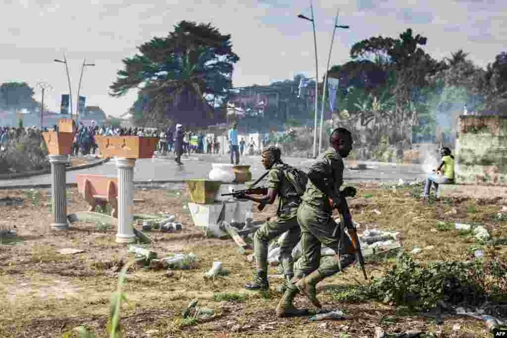 Gabonese soldiers run to take position as supporters of opposition leader Jean Ping protest in front of security forces blocking the electoral commission in Librevill.