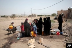 FILE - People fill buckets with water from a well that is alleged to be contaminated water with the bacterium Vibrio cholera, on the outskirts of Sanaa, Yemen, July, 12, 2017.