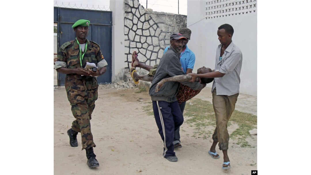 Somali police men in Mogadishu carry a soldier who was injured as two suicide bombers tried to blow up the constituent assembly venue before being shot dead by security forces, Aug.1, 2012.