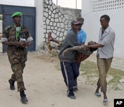 Somali police men in Mogadishu carry a soldier who was injured as two suicide bombers tried to blow up the constituent assembly venue before being shot dead by security forces, Aug.1, 2012.