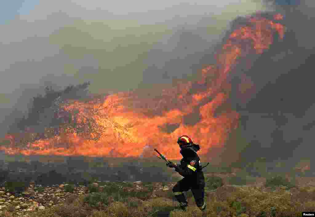 A Greek firefighter runs to safer ground as a forest fire rages in Marathon near Athens, Greece.