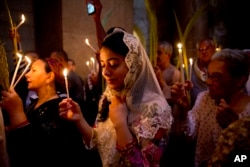 FILE - Christians hold candles during the Palm Sunday Mass at the Church of the Holy Sepulchre, traditionally believed by many to be the site of the crucifixion and burial of Jesus Christ, in Jerusalem's Old City, April 24, 2016.