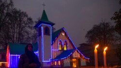 An Indian Christian devotee prays after lighting a candle outside the illuminated Holy Family Catholic Church on Christmas Eve in Srinagar, Indian-controlled Kashmir, Dec. 24, 2021.