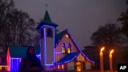 An Indian Christian devotee prays after lighting a candle outside the illuminated Holy Family Catholic Church on Christmas Eve in Srinagar, Indian-controlled Kashmir, Dec. 24, 2021.