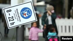 Para pejalan kaki berjalan melintas sebuah peringatan untuk selalu mengenakan masker di tengah pandemi virus corona (Covid-19) di Frankfurt, Jerman, 29 Oktober 2020. (Foto: Reuters)