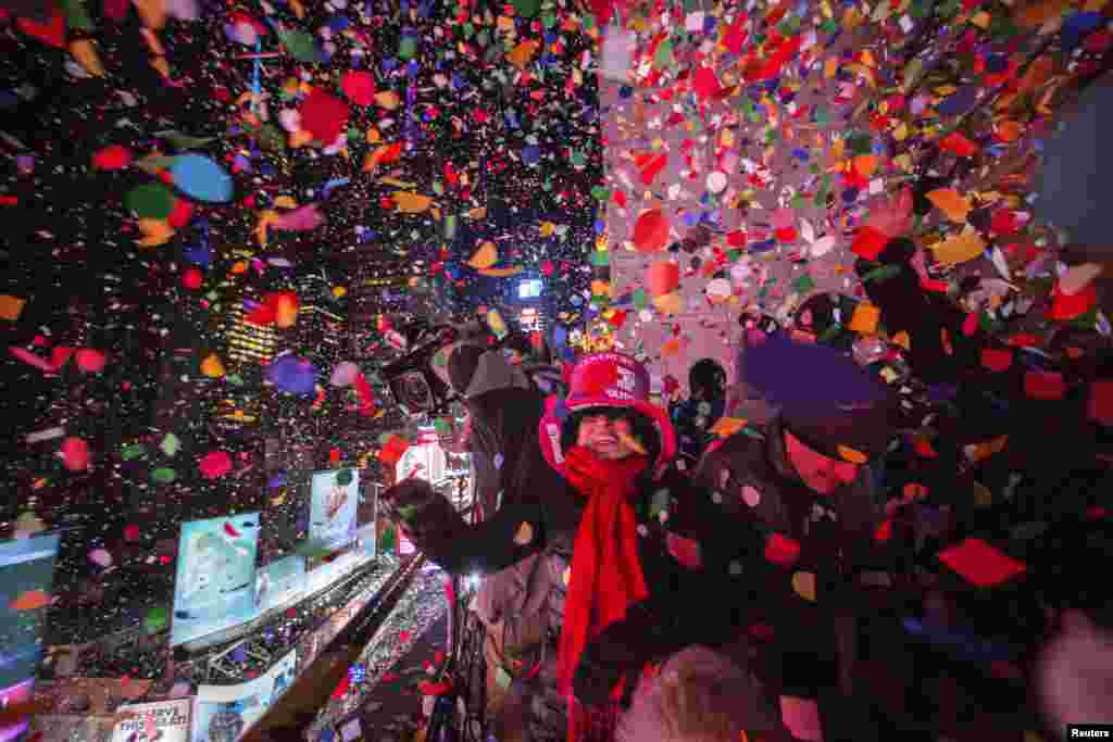 Revelers toss confetti over Times Square from a hotel after the clock struck midnight during New Year&#39;s Eve celebrations in New York.