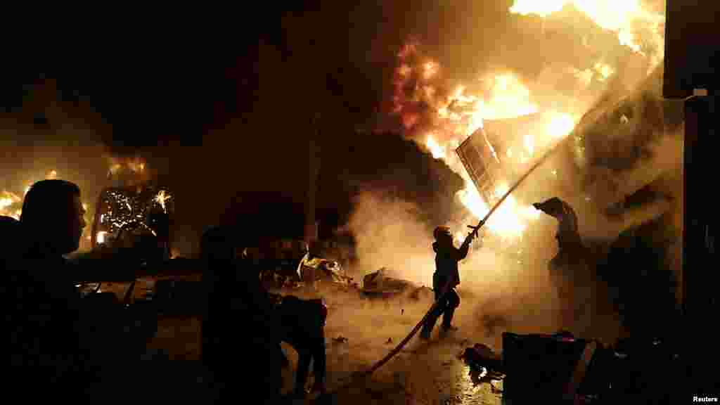 A firefighter douses flames after Syrian state media reported an Israeli missile attack in a container storage area, at the Syrian port of Latakia, Syria, in this handout picture released by SANA.