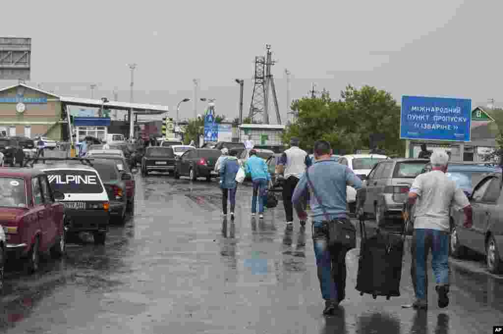 People carry their belongings as they walk to cross the border into Russia at the Ukrainian-Russian border checkpoint in Izvaryne, eastern Ukraine, June 20, 2014. 