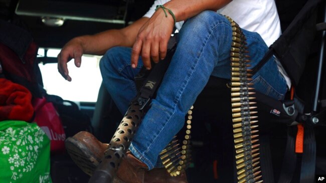 Seorang anggota kelompok pengamanan swakarsa yang dikenal dengan nama Pueblos Unidos duduk dengan amunisi dalam aksi protes di Nuevo Urecho, Michoacan, pada 27 November 2021. (Foto: AP)