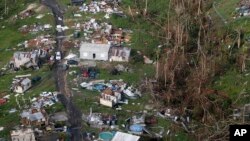 FILE - In this Sept. 28, 2017, photo, damaged and destroyed homes are seen in the aftermath of Hurricane Maria in Toa Alta, Puerto Rico. So far this year the United States has had 15 weather disasters that caused at least $1 billion in damage. 