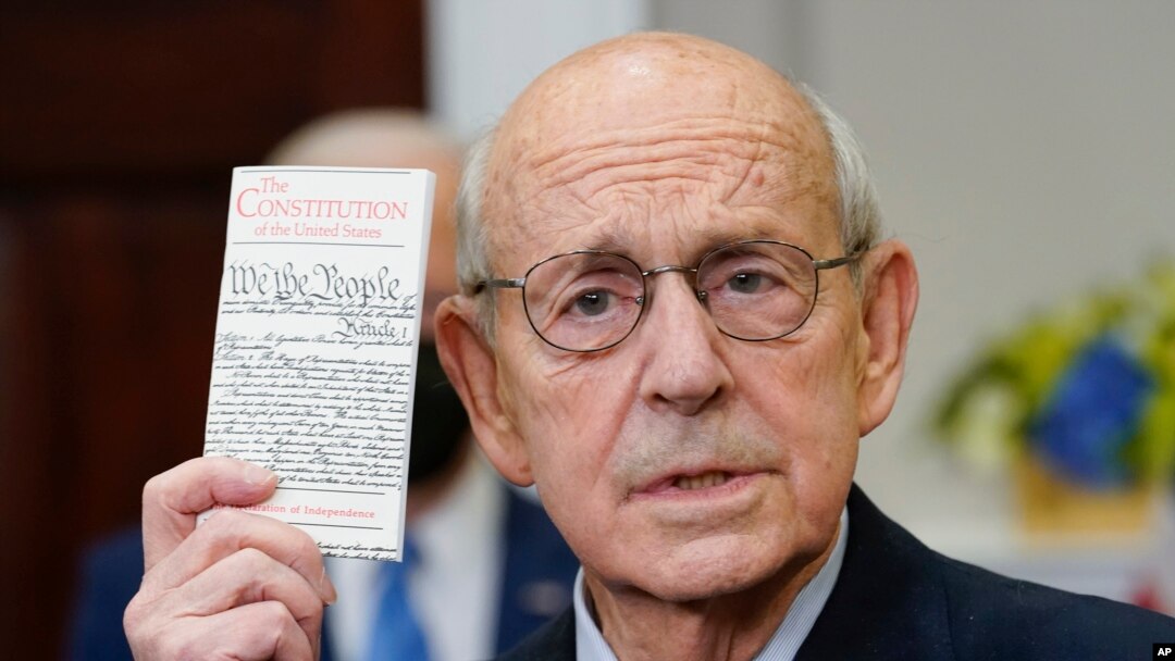 FILE – Supreme Court Justice Stephen Breyer holds up a copy of the U.S. Constitution as he announces his retirement in the Roosevelt Room of the White House in Washington, Jan. 27, 2022.