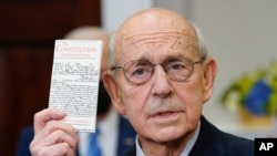 FILE – Supreme Court Justice Stephen Breyer holds up a copy of the U.S. Constitution as he announces his retirement in the Roosevelt Room of the White House in Washington, Jan. 27, 2022.