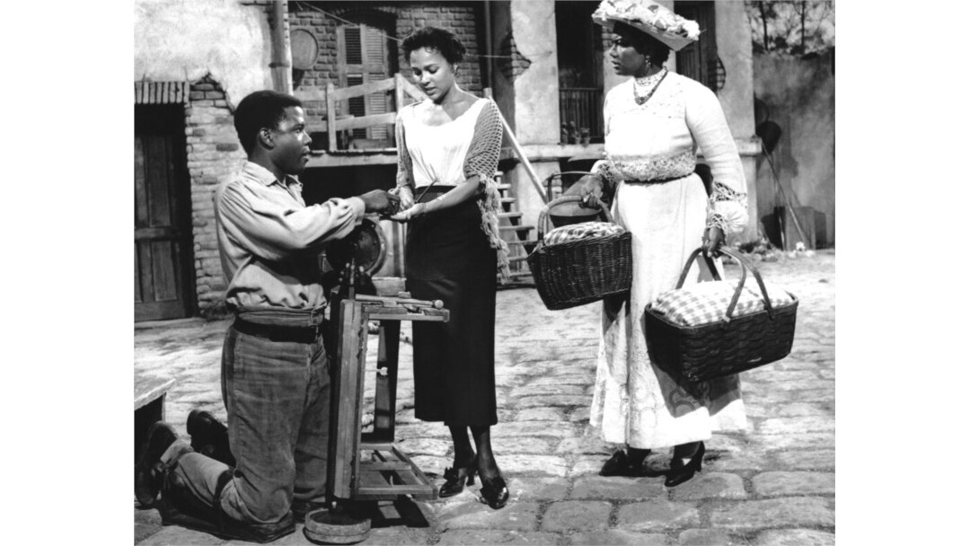 FILE - Kneeling on his crippled legs, Porgy, played by Sidney Poitier, urges Bess (Dorothy Dandridge, center) to join Maria (Pearl Bailey) at the picnic, in this scene from the movie version of "Porgy and Bess," Nov. 17, 1958.