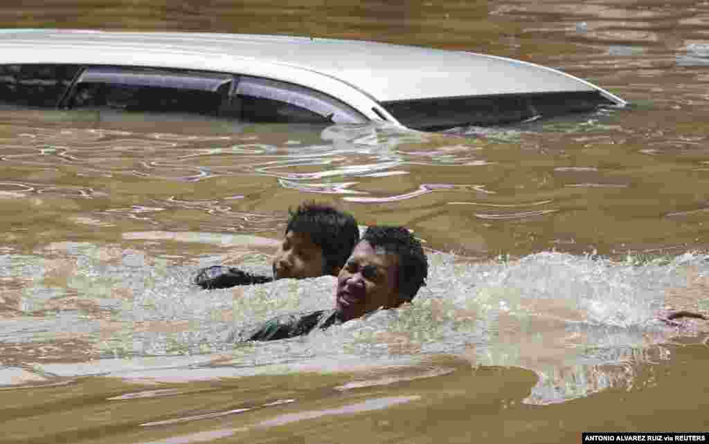 People swim through a flooded neighborhood following heavy rains in Jakarta, Indonesia, Feb. 20, 2021.