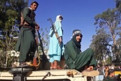 Para pejuang Taliban berdiri di atas kendaraan di sepanjang pinggir jalan Herat, kota terbesar ketiga di Afghanistan, 13 Agustus 2021. (AFP)