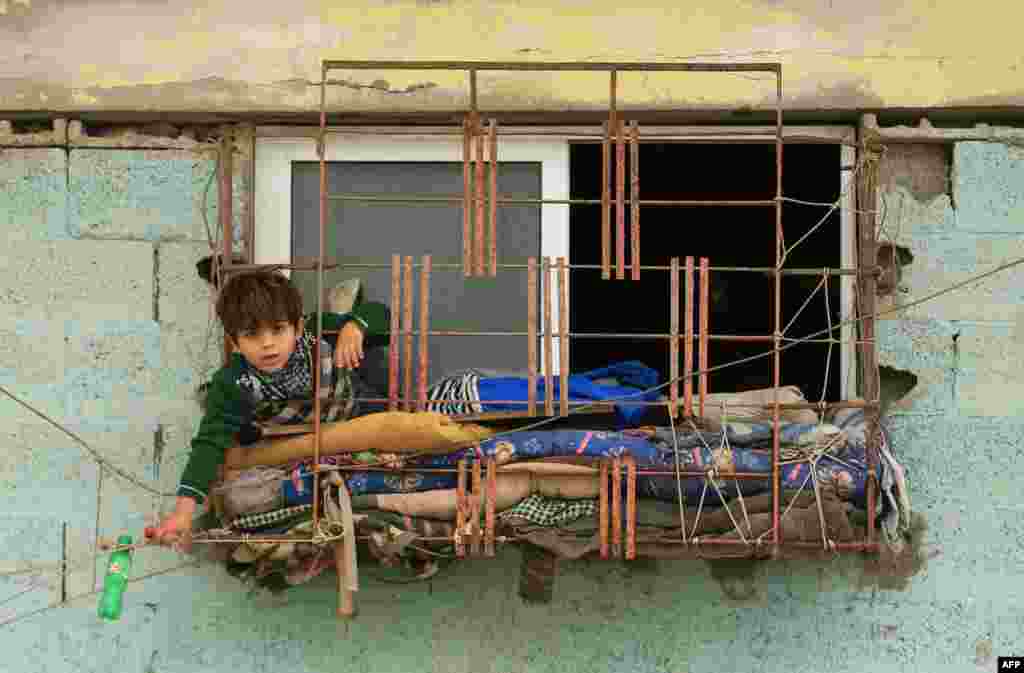 A Palestinian boy leans over the window of his house in Gaza City.