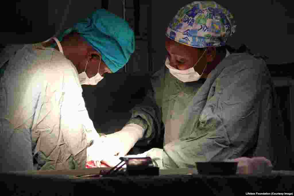 Surgeon and nurse anaesthetist work intently together to safety remove baby via emergency Caesarean section.