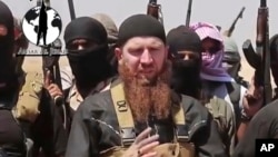 FILE - Abu Omar al-Shishani, also known as "Omar the Chechen," stands next to Islamic State fighters as they declare elimination of border between Iraq and Syria.