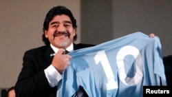 Mantan Bintang Sepakbola Argentina Diego Maradona hmemegang kaos dengan nomor punggungnya dalam sebuah konprensi pers di Napoli, Februari 2013. 
