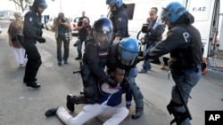 Italian police officers in riot gear remove a migrant in Ventimiglia, at the Italian-French border, June 16, 2015.