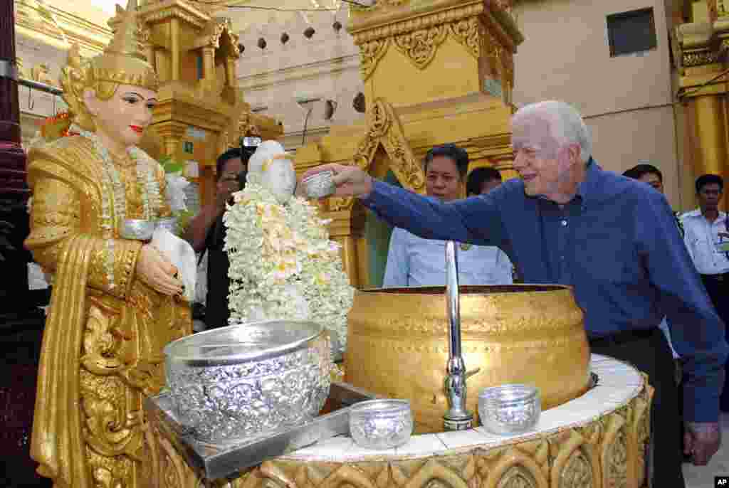 Former U.S. President Jimmy Carter pours water on a Buddha statue as he visits the famed Shwedagon Pagoda Friday, April 5, 2013 in Yangon, Myanmar. Carter arrived in Myanmar Tuesday to support the country's ongoing democratic transition. (AP Photo/Khin Maung Win)