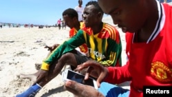 A Somali man browses the internet on his mobile phone at the beach along the Indian Ocean coastline in Somalia's capital Mogadishu, Jan. 10, 2014. 