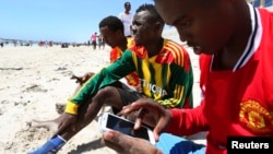 FILE - A Somali man browses the internet on his mobile phone at the beach along in Somalia's capital Mogadishu, Jan. 10, 2014. 