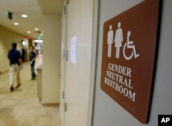 FILE- A sign marks the entrance to a gender-neutral restroom at the University of Vermont in Burlington, Vermont.