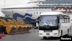 身穿防護服的司機駕駛一輛據信載有鑽石公主號郵輪上的老年遊客的大巴車離開橫濱港。（2020年2月14日）