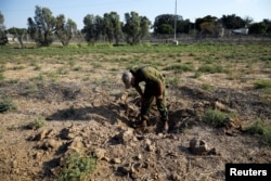 An Israeli soldier inspects a place where a rocket fell near the Israeli kibbutz of Nachal Oz, on the Israeli side of the Israel-Gaza border, July 14, 2018.