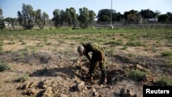 Un soldat israélien inspecte un endroit où une roquette est tombée près du kibboutz israélien de Nachal Oz, du côté israélien de la frontière entre Israël et Gaza, le 14 juillet 2018.