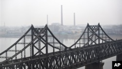 North Korean factories are seen behind a bridge at the waterfront of the Yalu River at the North Korean town of Sinuiju, opposite side of the Chinese border city of Dandong, China, Saturday, March 21, 2009. North Korea detained two Americans for illegally