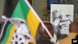 A photo of former South African president, late Nelson Mandela, right, is displayed during a remembrance ceremony in Qunu, South Africa, Saturday, Dec. 7, 2013.