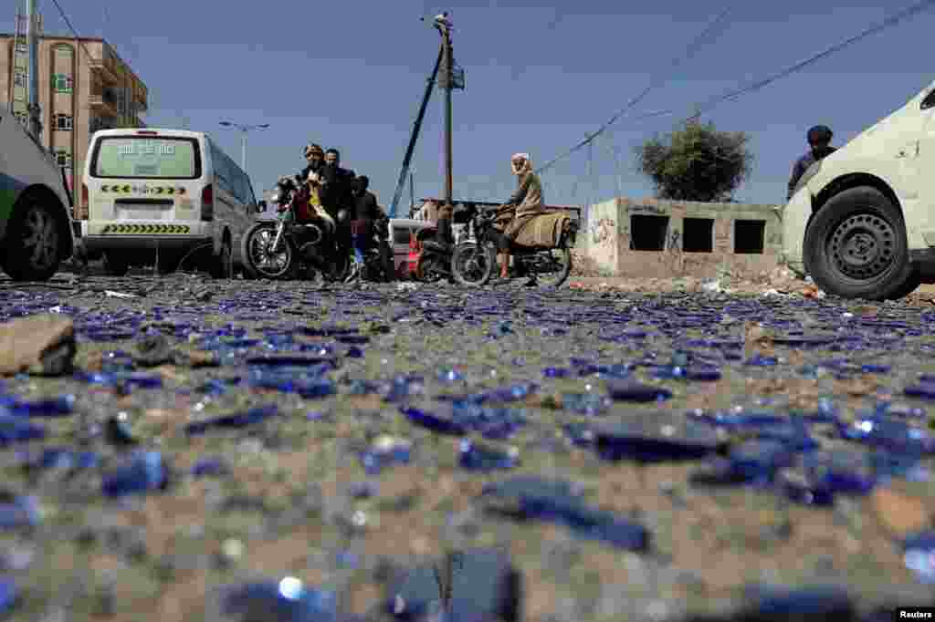 People ride on motorbikes at the scene of Saudi-led airstrike in Sana&#39;a, Yemen.