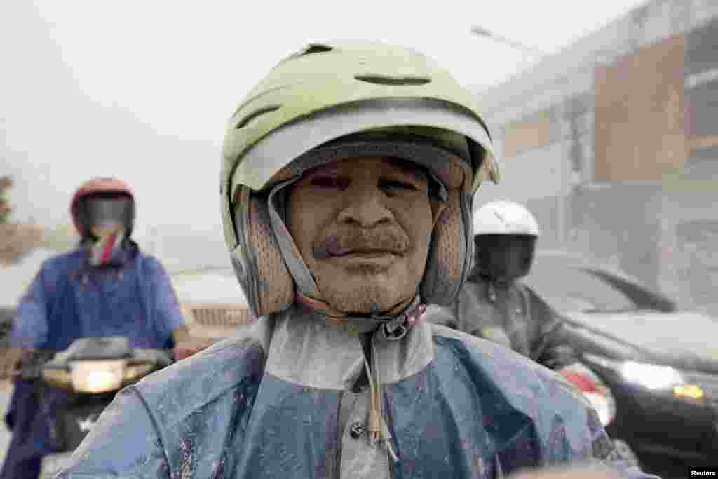 Seorang pengendara motor di Yogyakarta berselimut abu dari Gunung Kelud di Kediri, Jawa Timur, yang meletus Kamis malam (13/2). (Reuters/Dwi Oblo)