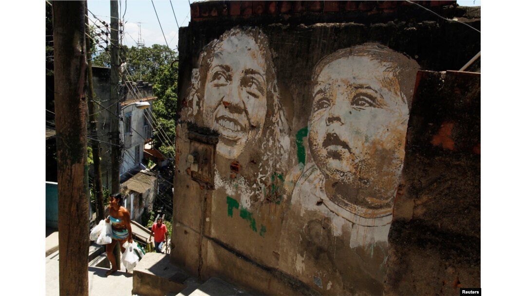 People walk past graffiti in the Morro da Providencia slum in Rio de Janeiro, Nov. 29, 2012. The artwork of Portuguese artist Alexandre Farto, a k a Vhils, decorates some walls with faces that represent the people who live in Providencia.