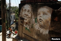 People walk past graffiti in the Morro da Providencia slum in Rio de Janeiro, Nov. 29, 2012. The artwork of Portuguese artist Alexandre Farto, a k a Vhils, decorates some walls with faces that represent the people who live in Providencia.