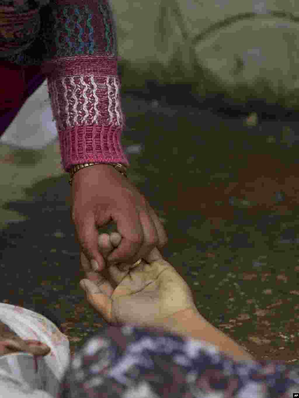 Seorang perempuan Nepal memegang tangan salah satu anggota keluarganya yang tewas akibat gempa bumi di sebuah rumah sakit di Kathmandu, Nepal.