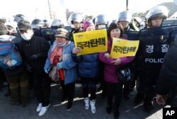 Protesters are pushed by police officers during a rally demanding the parliamentary impeachment of South Korean President Park Geun-hye in front of the National Assembly in Seoul, South Korea, Friday, Dec. 9, 2016.